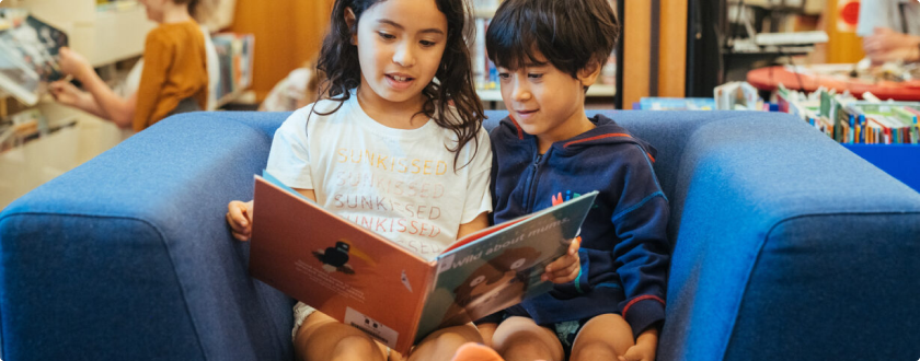 Two children reading a book at the library