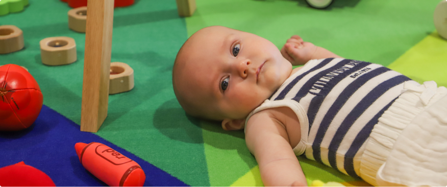 baby laying on floor playing at baby book club