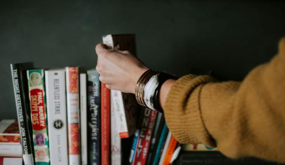 woman reaching for book on shelf