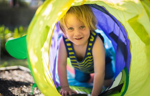 Young child crawling through play tunnel