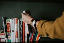 woman reaching for book on shelf